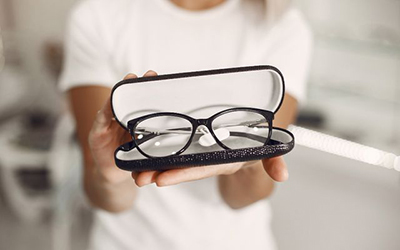 משקפי מולטיפוקל עם עדשות מולטיפוקל, המשקפיים בתוך קייס תוך כדי שמישהי מחזיקה ומציגה למצלמה את המשקפיים